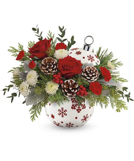 Sprinkle Sparkle Bouquet featuring red roses, mini-carnations, white button mums, pinecones, cedar, and dusty miller in a red snowflake ornament vase.