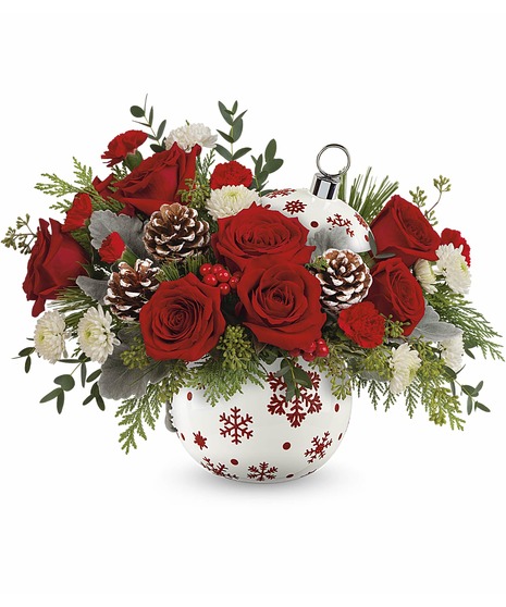 Sprinkle Sparkle Bouquet featuring red roses, mini-carnations, white button mums, pinecones, cedar, and dusty miller in a red snowflake ornament vase.